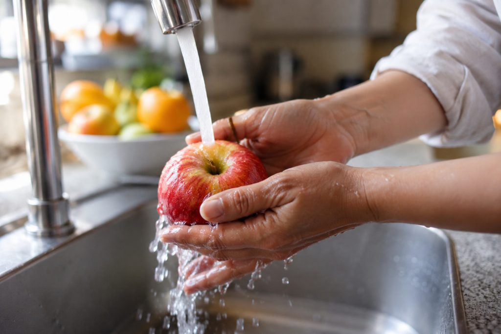 Manos lavando una manzana